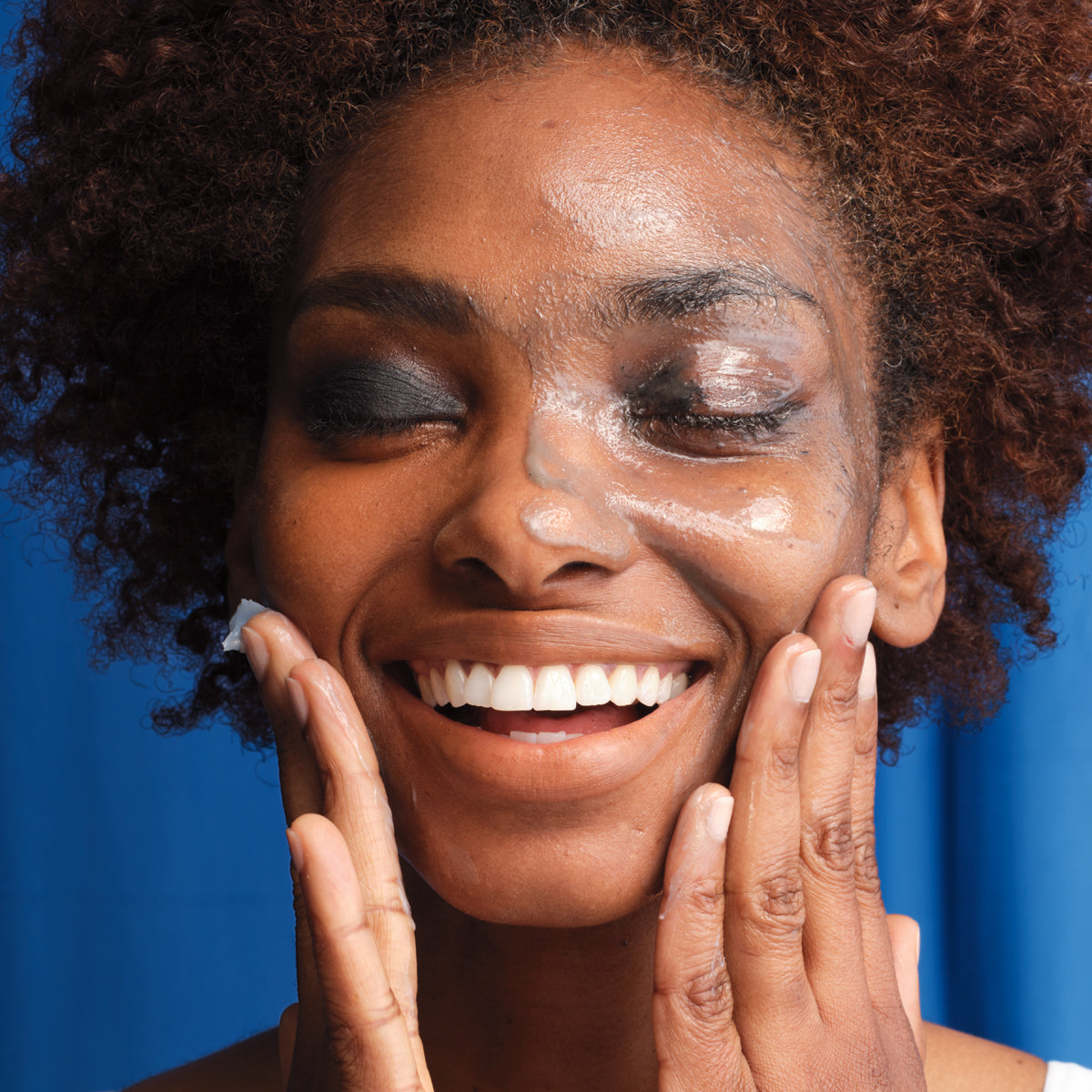 Woman washing face with The Indigo Cleansing Balm and visibly showing mascara removal.