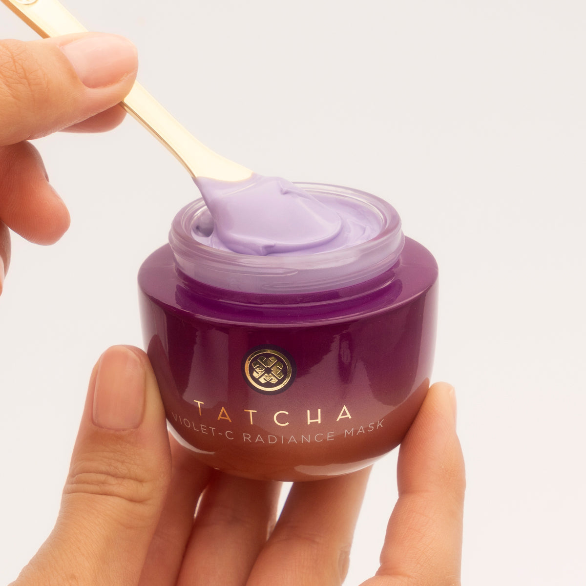 Tatcha Violet-C Radiance Mask with a hand holding the jar and a spoonful of mask.