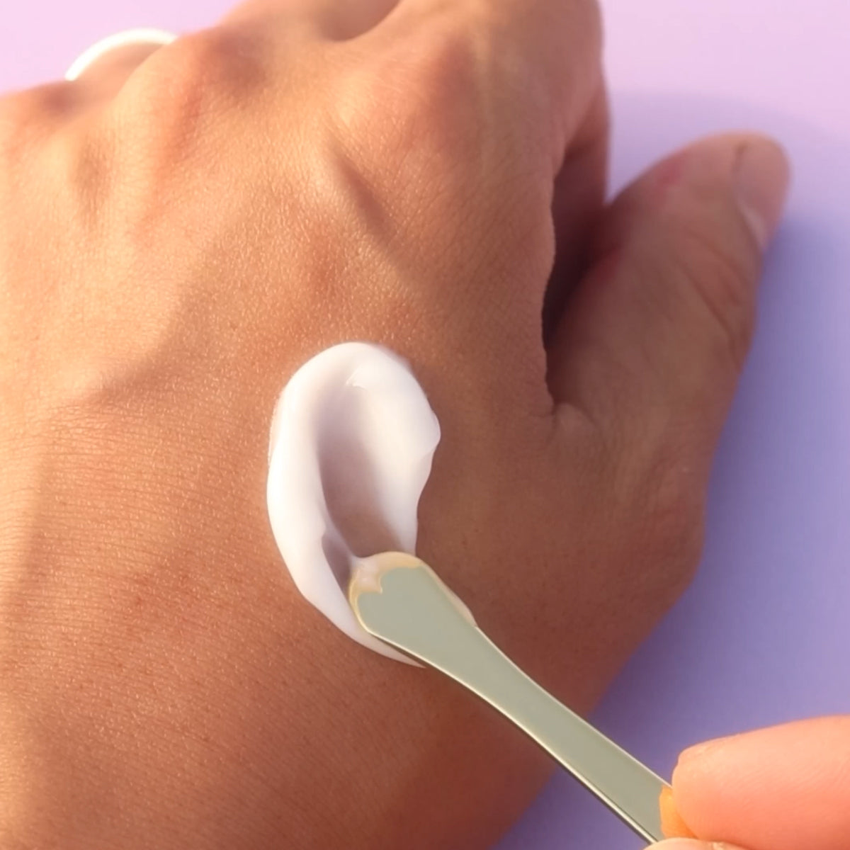 Ageless Enriching Renewal Cream texture applied on hand with gold spoon