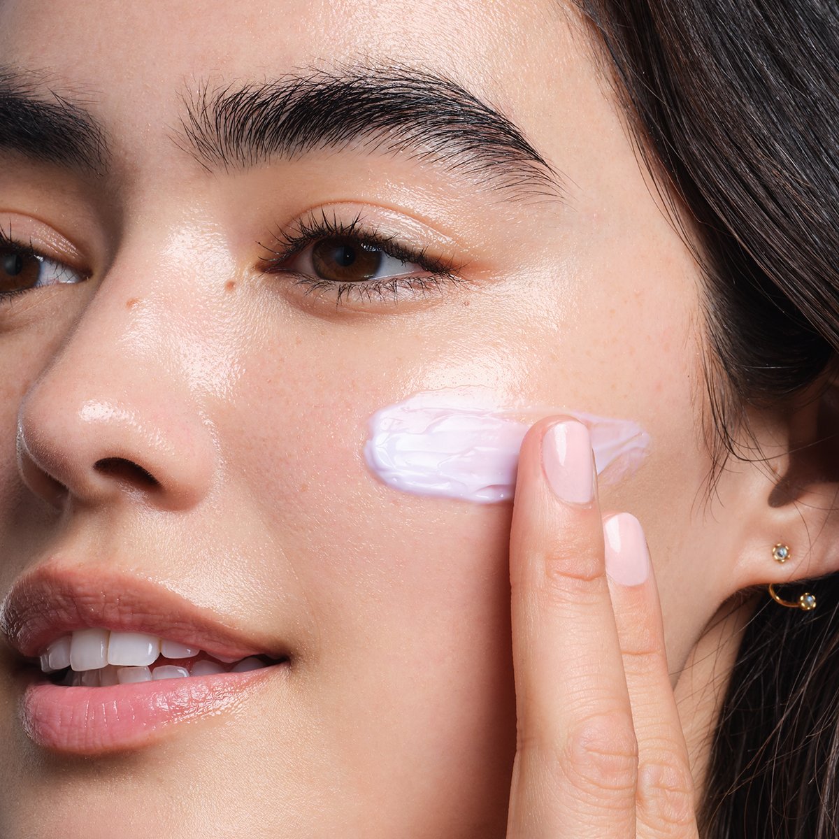 Woman applying The Dewy Skin Cream 
