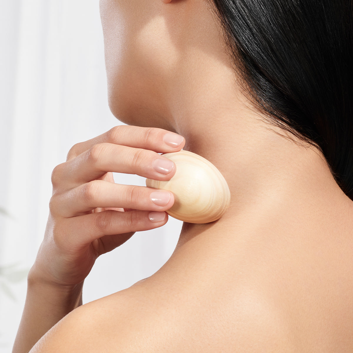 Model using The Hinoki Massage Egg on back of shoulder.