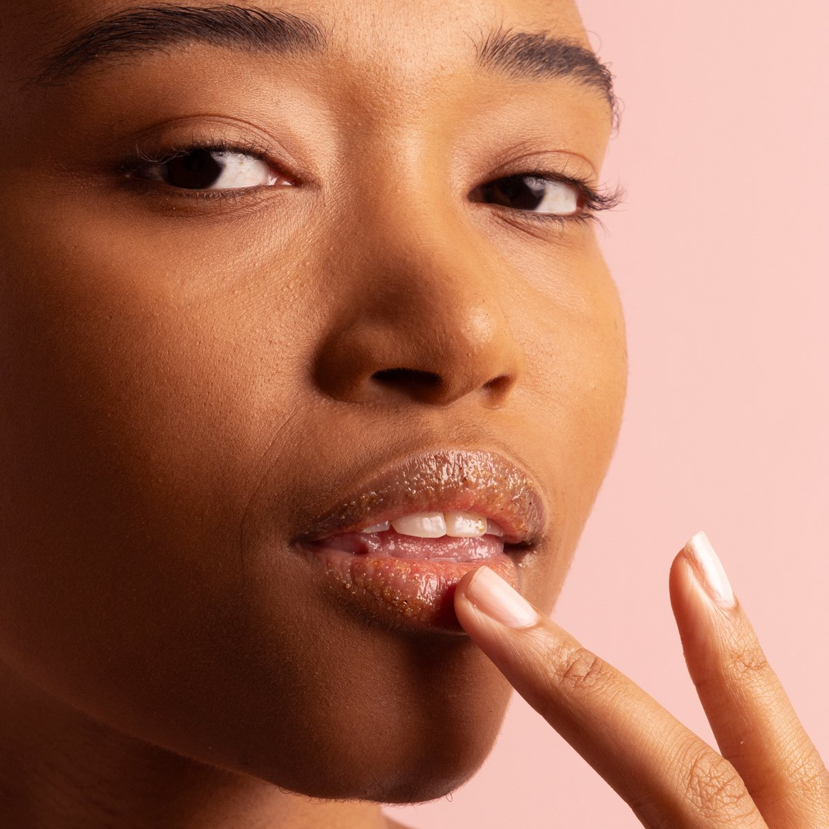 Model applying The Kissu Lip Scrub on lips.