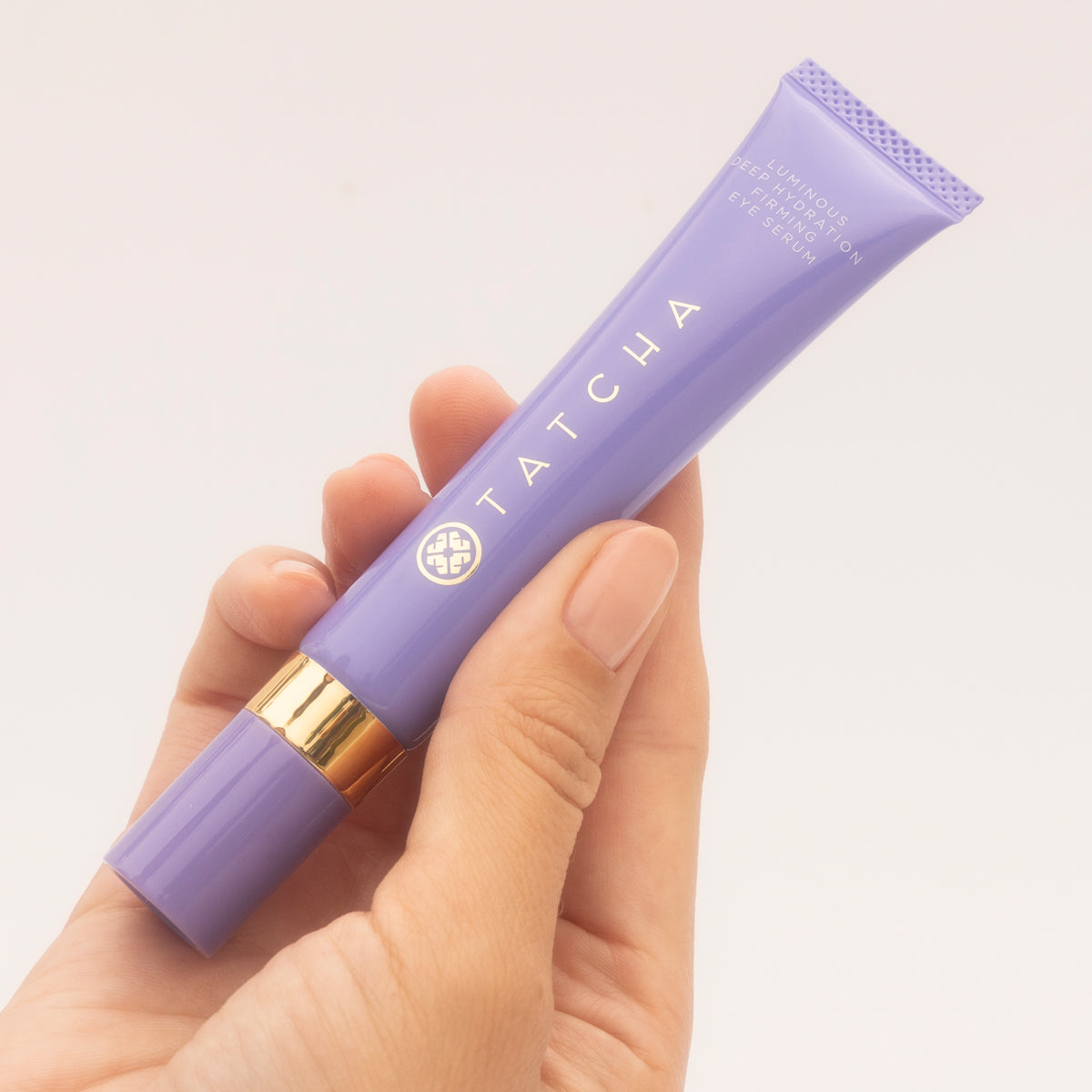 Model holding The Luminous Deep Hydration Firming Eye Serum.